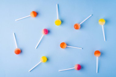 Mavi arka plan üst görünümünde dağınık lolipop şekerler