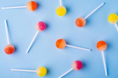 Mavi arka plan üst görünümünde dağınık lolipop şekerler
