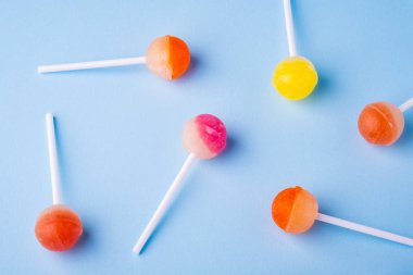 Mavi arka plan üst görünümünde dağınık lolipop şekerler