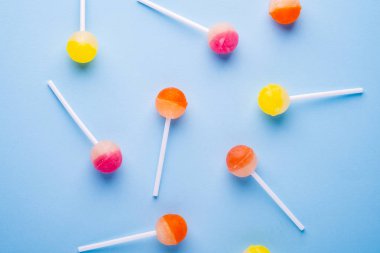 Mavi arka plan üst görünümünde dağınık lolipop şekerler