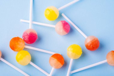 Mavi arka plan üst görünümünde dağınık lolipop şekerler