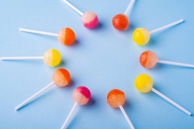 Mavi arka plan açısı görünümünde lolipop şekerleri daire