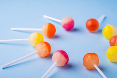 Mavi arka plan açısı görünümünde lolipop şekerleri daire