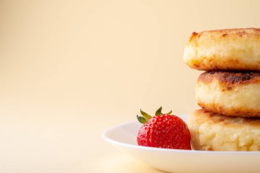 Sarı arka plan izole açı görünümünde beyaz plaka üzerinde bir çilek ile Süzme peynir krep