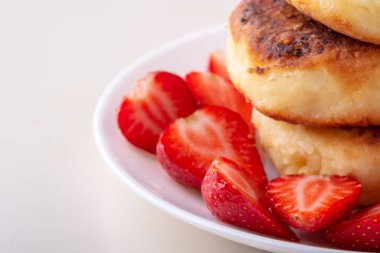 Beyaz tabak izole dilimlenmiş çilek ile Süzme peynir krep