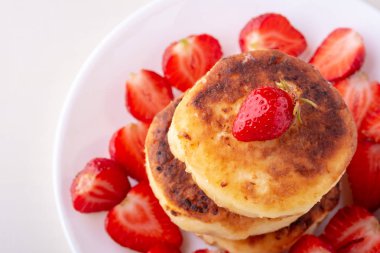 Beyaz tabak izole dilimlenmiş çilek ile Süzme peynir krep