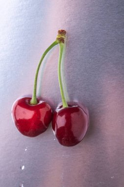 Parlak gümüş arka planda kök ile iki kiraz çilek