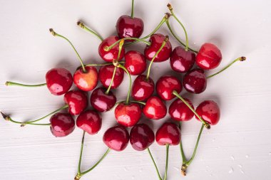 Ahşap beyaz arka plan ve su damlaları üst görünümü kök ile kopya boşluk kiraz meyveleri