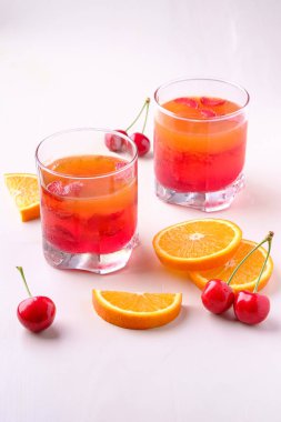 Yakındaki kiraz ve portakal dilimleri ile içecek cam çilek ile Jelly tatlı