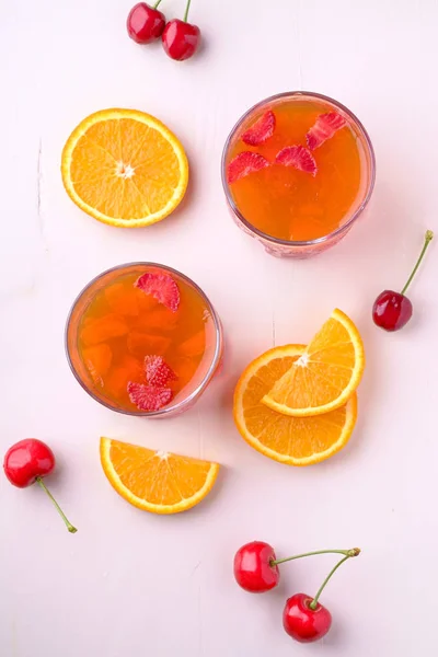 チェリーベリーとオレンジスライスのドリンクグラスにイチゴとイチゴのゼリーデザート近くのトップビューフラットレイ — ストック写真