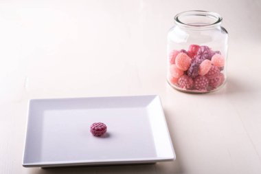 Beyaz arka plan izole cam kavanozda sulu çilek şeklinde şeker kamışı tatlılar ile beyaz plaka üzerinde bir şeker kamışı