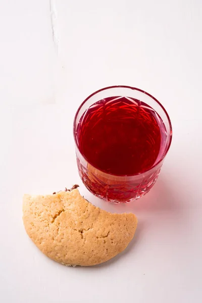 Homemade bitten shortbread chocolate cookie with stewed fruit red compote drink in glass on white wooden table