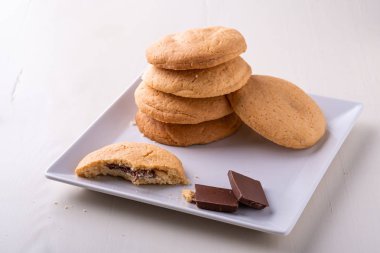 Bir ısırık kurabiye ve beyaz tabak ahşap masa üzerinde çikolata iki adet ile shortbread çikolatalı kurabiye ev yapımı yığını