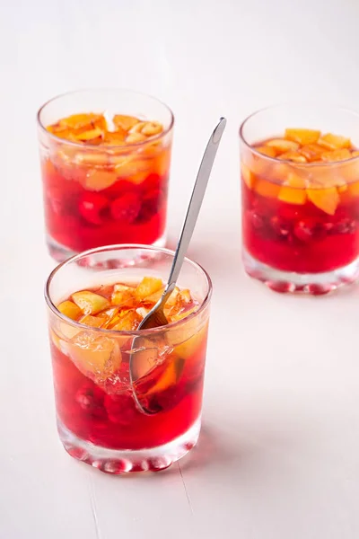 フルーツアプリコットラズベリーとジェリーデザートは 単一のスプーン黄色の赤い夏の白い背景が分離された3つの飲み物のグラスで — ストック写真