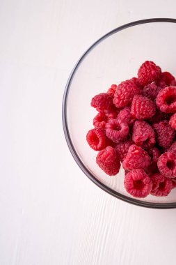 Şeffaf cam kase plaka ahududu kırmızı çilek beyaz arka plan kopya alanı makro lezzetli tatlı parlak