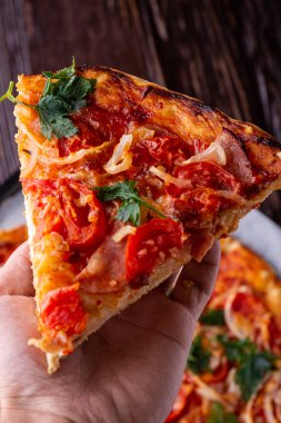 Taze pişmiş sıcak pizza dilim insan elinde peynir jambon et domates soğan maydanoz ev yapımı tarifi koyu ahşap masa arka plan yakın kadar makro