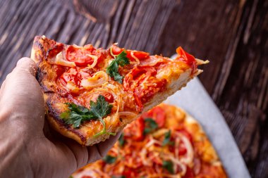 Taze pişmiş sıcak pizza dilim insan elinde peynir jambon et domates soğan maydanoz ev yapımı tarifi koyu ahşap masa arka plan yakın kadar makro