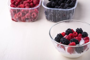 Ahududu ile dondurma, beyaz arka planda çilek iki konteyner yakın cam kase böğürtlen