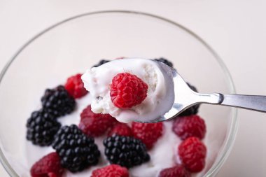 Ahududu ile dondurma, beyaz arka planda cam kase kaşık ile böğürtlen çilek