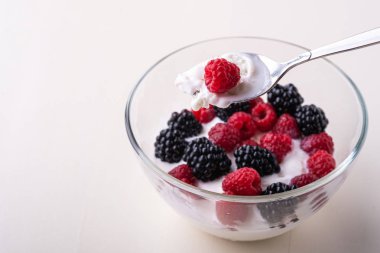 Ahududu ile dondurma, beyaz arka planda cam kase kaşık ile böğürtlen çilek