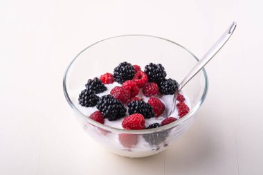 Ahududu ile dondurma, beyaz arka planda cam kase kaşık ile böğürtlen çilek