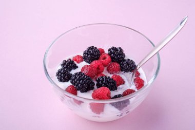 Ahududu ile dondurma, pembe arka planda cam kase kaşık ile böğürtlen çilek