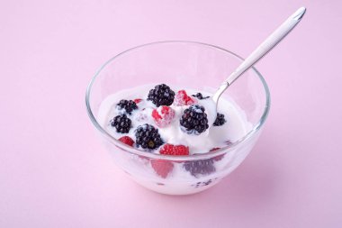 Ahududu ile dondurma, pembe arka planda cam kase kaşık ile böğürtlen çilek