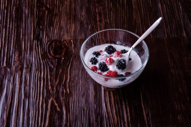 Ahududu ile dondurma, koyu ahşap arka planda cam kase kaşık ile böğürtlen çilek