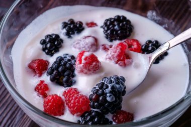 Ahududu ile dondurma, koyu ahşap arka planda cam kase kaşık ile böğürtlen çilek
