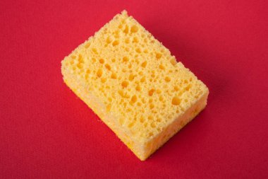 Kırmızı renkli kağıt arka plan üzerinde tek sarı sünger, kopya alanı