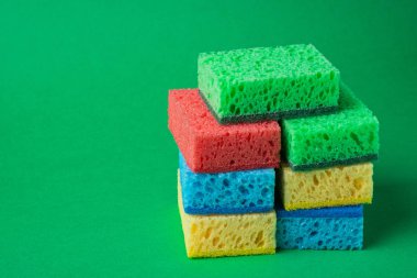 Yeşil kağıt arka plan üzerinde kırmızı, mavi, yeşil, sarı renklerde sünger yığını, yakın