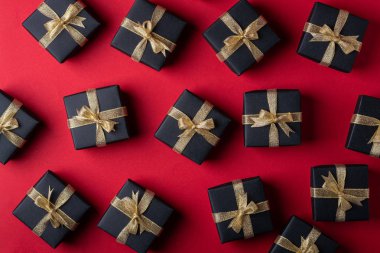 Kırmızı kağıt arka plan üzerinde altın kurdeleler ile Siyah hediye kutusu, desen, doku, izole, üst görünüm, düz yatıyordu