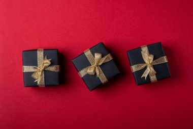 Kırmızı kağıt arka plan, doku, izole, üst görünüm, düz yatıyordu, kopyalama alanı üzerinde doğrultusunda altın kurdeleler ile üç siyah hediye kutusu