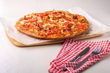Tavuk eti ile sıcak ev yapımı pizza, domates, kırmızı masa örtüsü üzerinde çatal çatal ve bıçak ile yakın soğan, açı görünümü, seçici odak