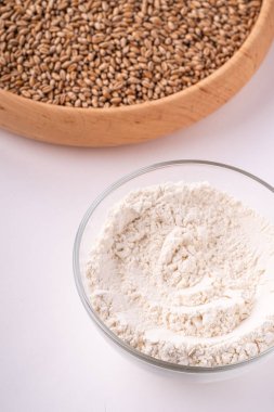 Cam kase, açı görünümü, beyaz arka plan üzerinde izole, kopya alanı buğday unu ile yakın ahşap kase buğday tohumu taneleri