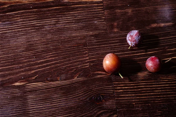 Verstreute Reife Süße Pflaumenfrüchte Auf Dunklem Stimmungsvollem Holztischhintergrund Hartes Licht — Stockfoto