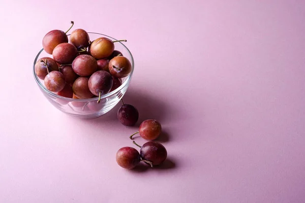 Ripe Sweet Plum Fruits Glass Bowl Scattered Plums Pink Background — Stock Photo, Image