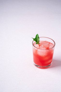Beyaz arka planda cam içecek buz küpleri ve yeşil nane yaprağı ile taze soğuk karpuz suyu, kopya alanı, açı görünümü