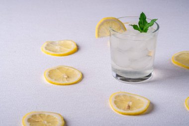 Buz küpleri, limon dilimi ve nane yaprağı limon dilimleri yakın, beyaz gri arka plan, açı görünümü, seçici odak ile cam taze soğuk berrak su içeceği