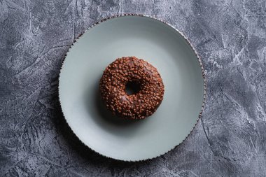 Gri tabağa serpiştirilmiş çikolatalı çörek, beton desenli arka planda tatlı jöleli tatlı yiyecekler, üst manzara.