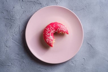 Pembe tabağa serpiştirilmiş pembe donut, beton desenli arka planda tatlı jöleli tatlı yiyecekler, üst manzara.