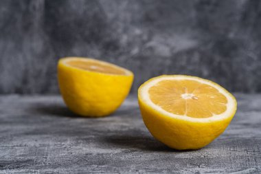 İki limon dilimi, gri beton arka planda tropikal turunçgil meyvesi, açı manzaralı.