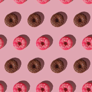 Pembe ve çikolatalı çörekler, pürüzsüz desenli, tatlı jöleli tatlı yiyecekler, pembe minimal arka plan, üst manzara.