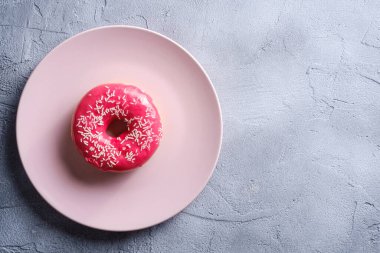 Pembe tabağa pembe çörekler serpiştirilmiş, tatlı tatlı yiyecekler beton desenli arka plan, üst görünüm kopya alanı