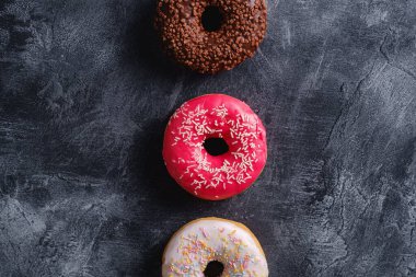 Çikolata, pembe ve vanilyalı çörekler, tatlı jöleli tatlı yiyecekler koyu beton desenli arka plan, üst görünüm