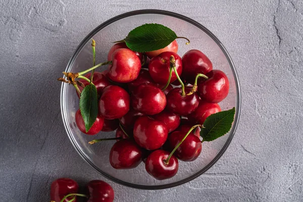Friss Érett Cseresznyefélék Zöld Levelekkel Üvegtálban Nyári Vitaminbogyók Szürke Háttéren — Stock Fotó