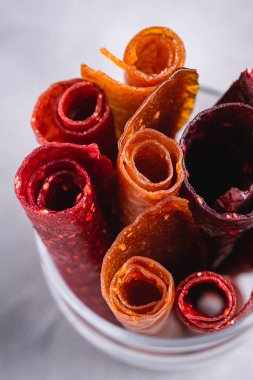 Taş zeminde cam bardakta meyveli pastil. Organik şekersiz rulo yiyecek ahududu, çilek, şeftali ve elmadan yapılır. Vejetaryen ev yapımı tatlılar. Açı görünümü makrosu