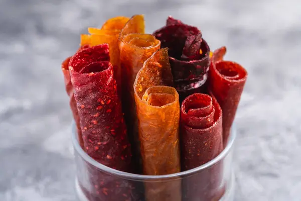 Taş zeminde cam bardakta meyveli pastil. Organik şekersiz rulo yiyecek ahududu, çilek, şeftali ve elmadan yapılır. Vejetaryen ev yapımı tatlılar. Açı görünümü makrosu