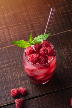 Naneli taze buzlu meyve suyu, bardakta ahududu limonatası, kahverengi ahşap arka planda pipetler, seçici bakış açısı