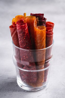 Taş zeminde cam bardakta meyveli pastil. Organik şekersiz rulo yiyecek ahududu, çilek, şeftali ve elmadan yapılır. Vejetaryen ev yapımı tatlılar. Açı görünümü